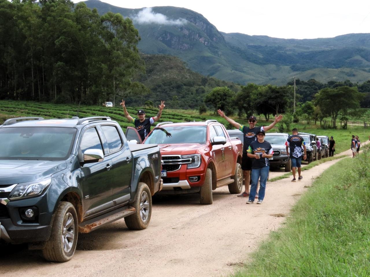 Comboio de picapes 4x4 com grupo comemorando na trilha